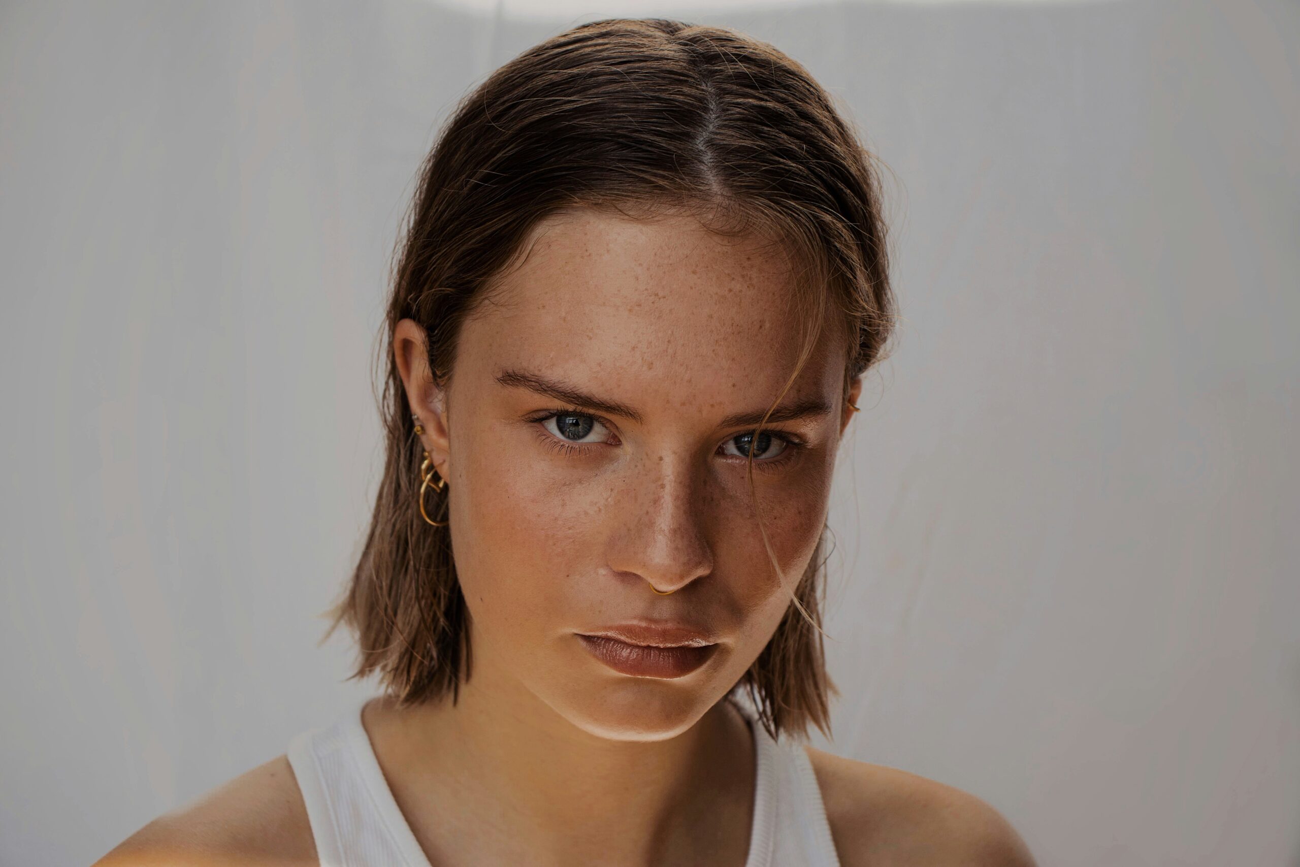 Confidence in Clean Beauty – Natural Cosmetics Close-up portrait of a confident young woman with natural freckles and minimal makeup, symbolizing clean, natural, cosmetics